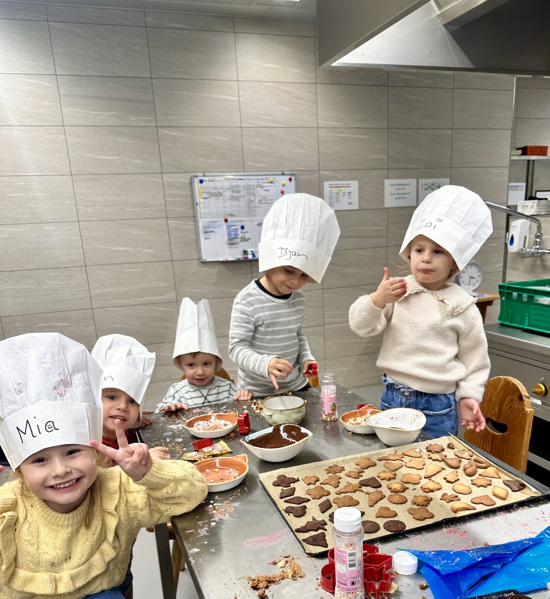 Kinder mit Kochmützen backen Guetzli in der Bären-Küche